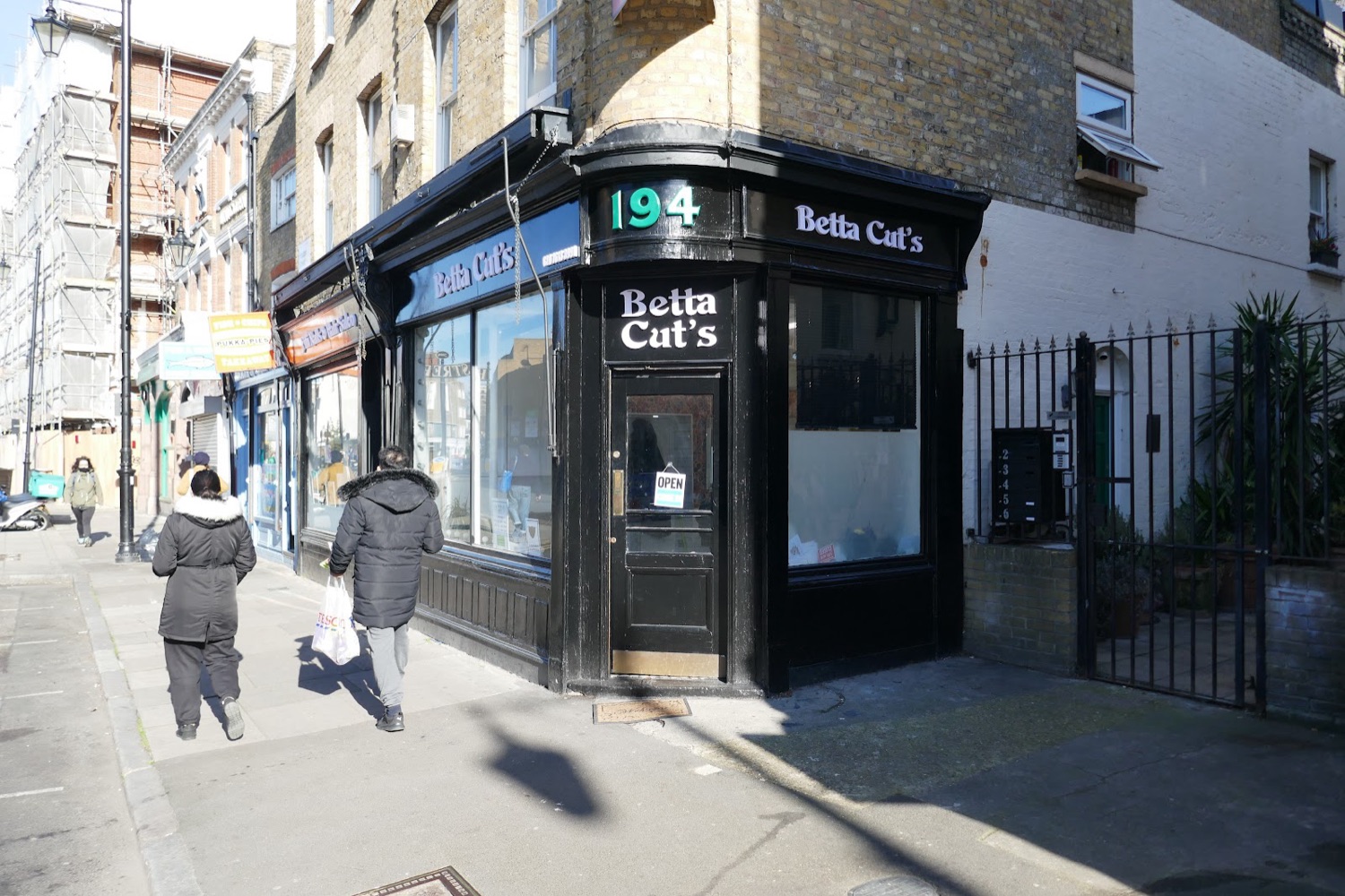 The corner of Hoxton Street and Nuttall Street showing the Betta Cut's Barber's shop at number 194 in the sunshine.