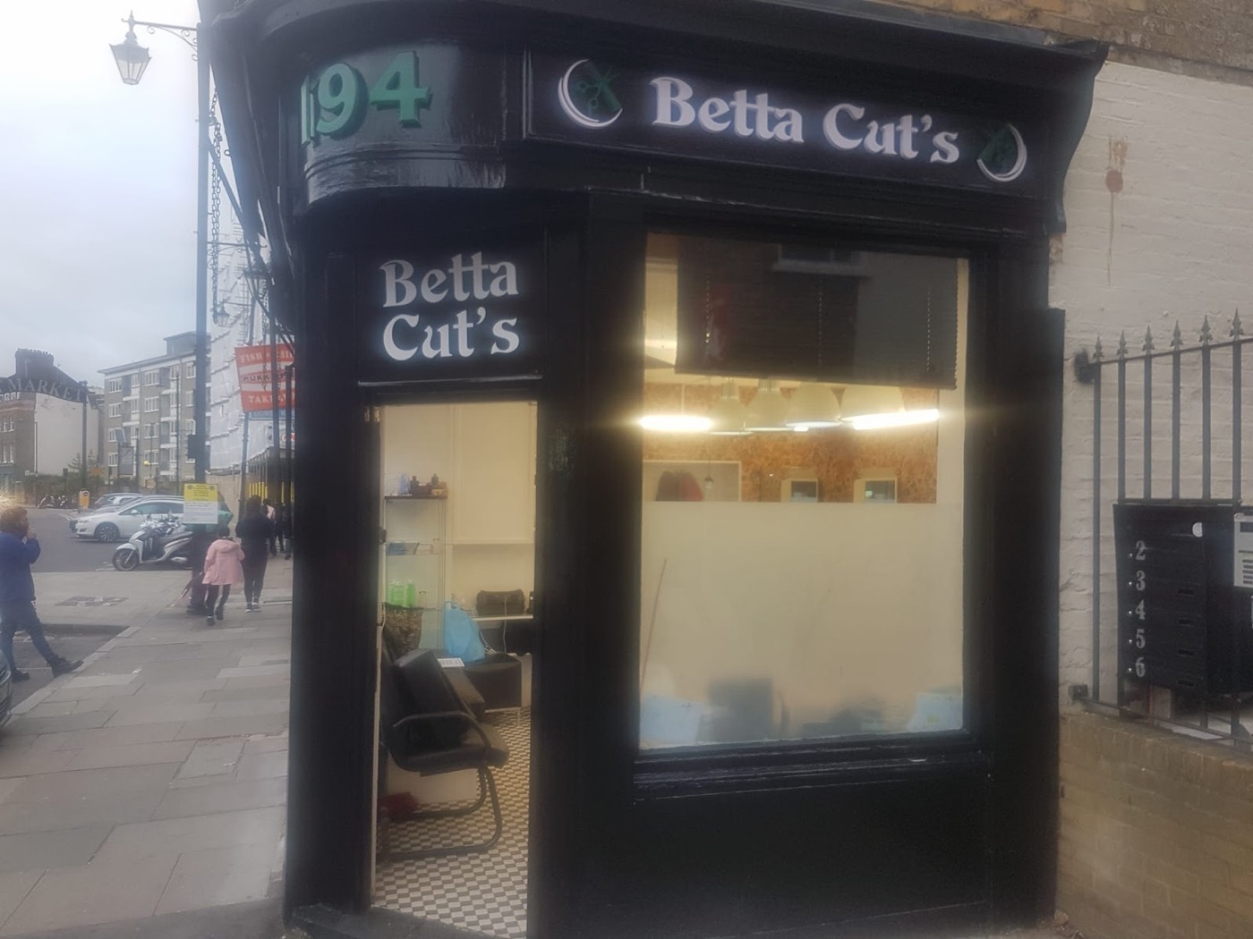 Inside Betta Cut's Barber's, seen through the corner window, barber's chair, checkerboard floor and warm patterned wall.